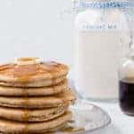 Image of a stack of pancakes with homemade pancake mix in the background.