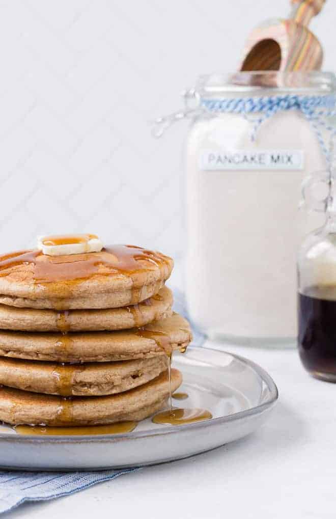 Image of a stack of pancakes with homemade pancake mix in the background.