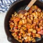 Apple compote in a cast iron skillet, with a spoon.