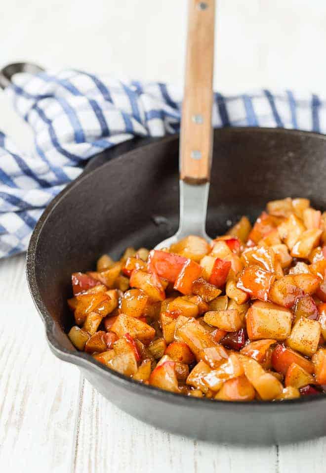 Apple compote in a cast iron skillet, with a spoon.