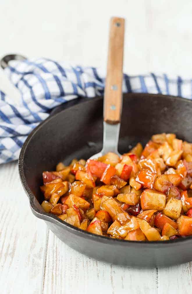 Apple compote in a cast iron skillet, with a spoon.