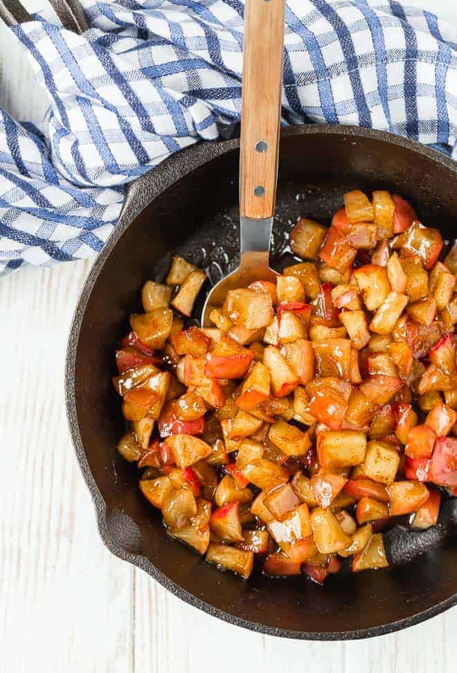 Apple compote in a cast iron skillet, with a spoon.