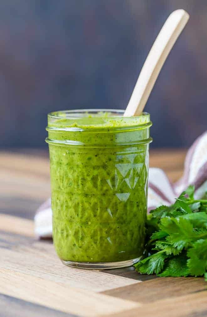 Image of freshly made salsa verde in a jar, with a spoon inserted