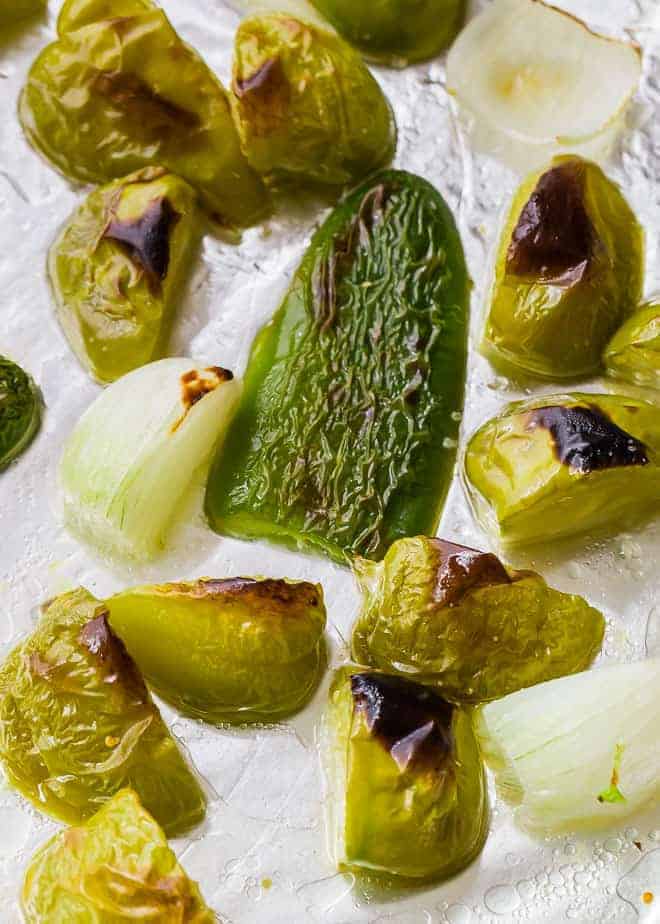 Image of roasted vegetables for salsa verde on a foil-lined sheet pan.