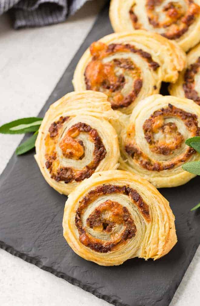 Sausage pinwheels made with puff pastry on a black slate board.