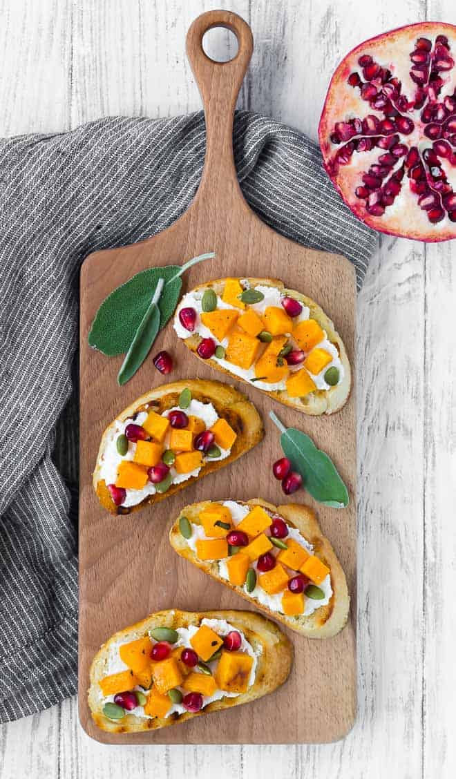 Photo of four squash crostini arranged on a wooden platter.