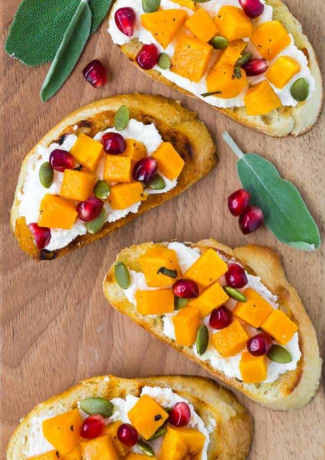 Image of butternut squash crostini topped with pomegranate and pepitas.