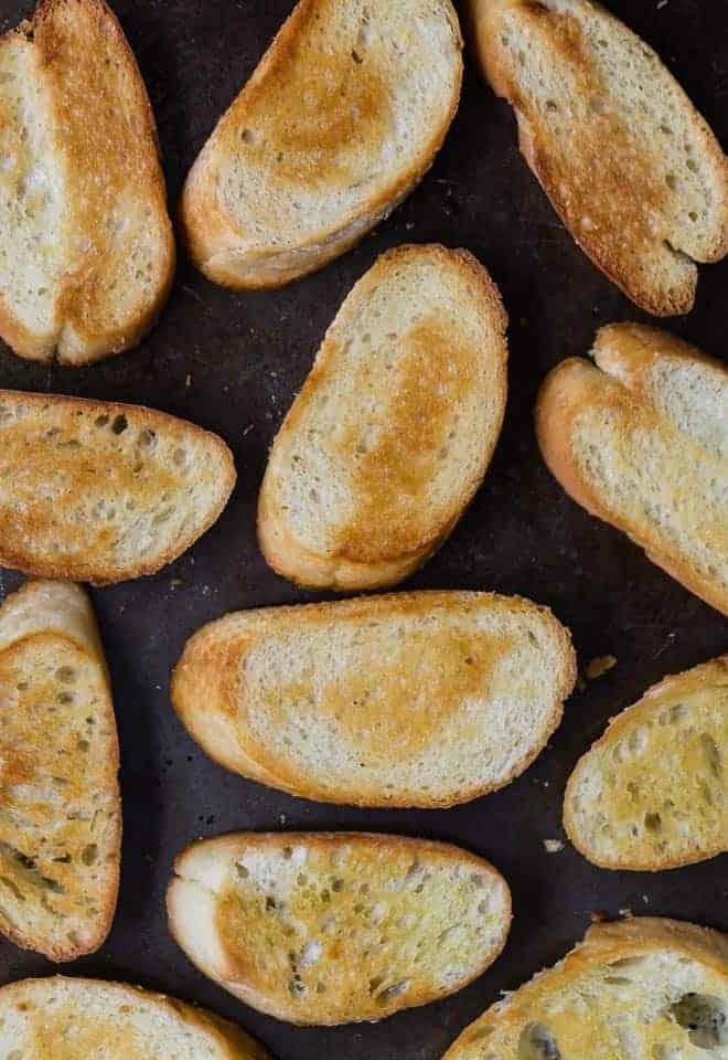Photograph of crostini baked on a sheet pan.