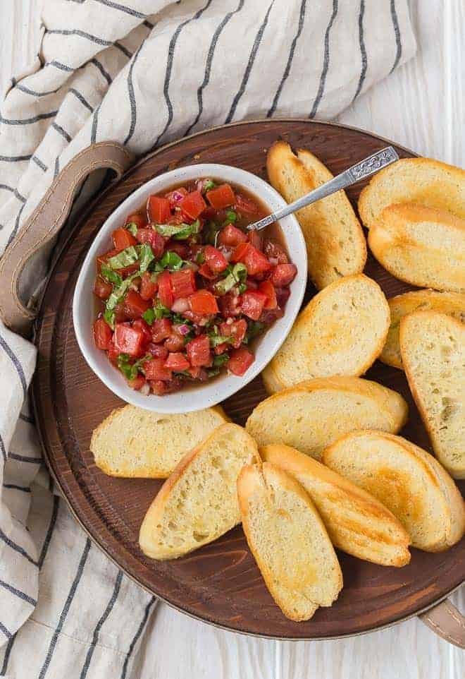 Image of the best tomato bruschetta recipe in a bowl served with crostini.