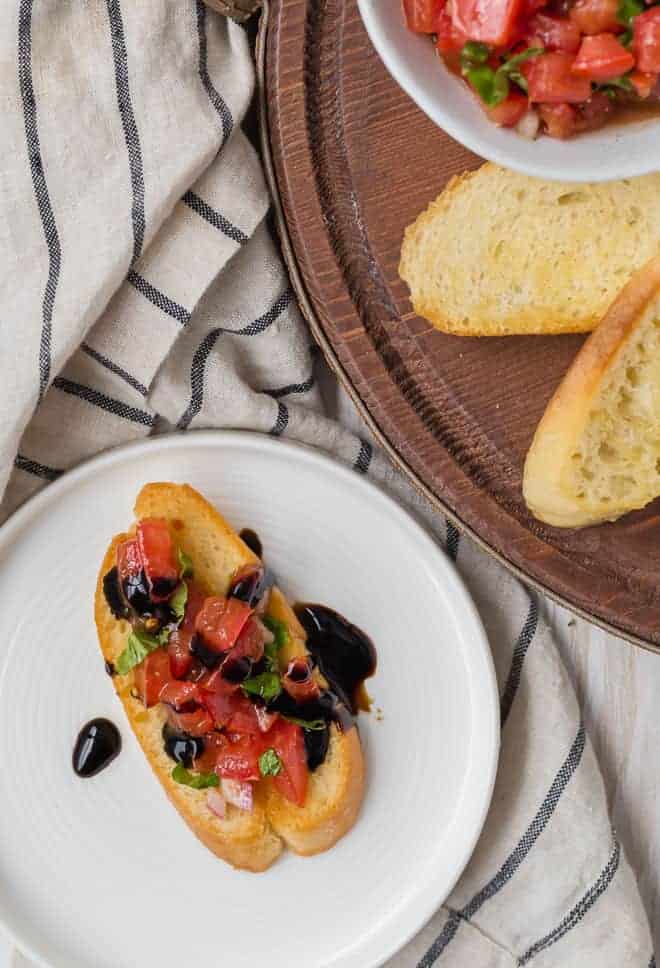 Photograph of classic tomato bruschetta with basil and a balsamic glaze.