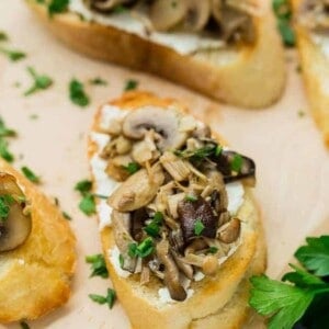 image of wild mushroom crostini with goat cheese, garnished with fresh parsley. Arranged with multiple crostini