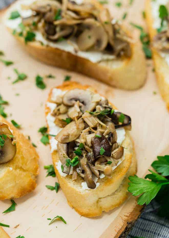 image of wild mushroom crostini with goat cheese, garnished with fresh parsley. Arranged with multiple crostini