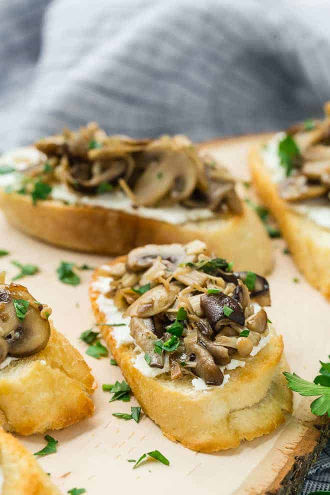 image of goat cheese and assorted sauteed mushrooms on a piece of crostini toast.