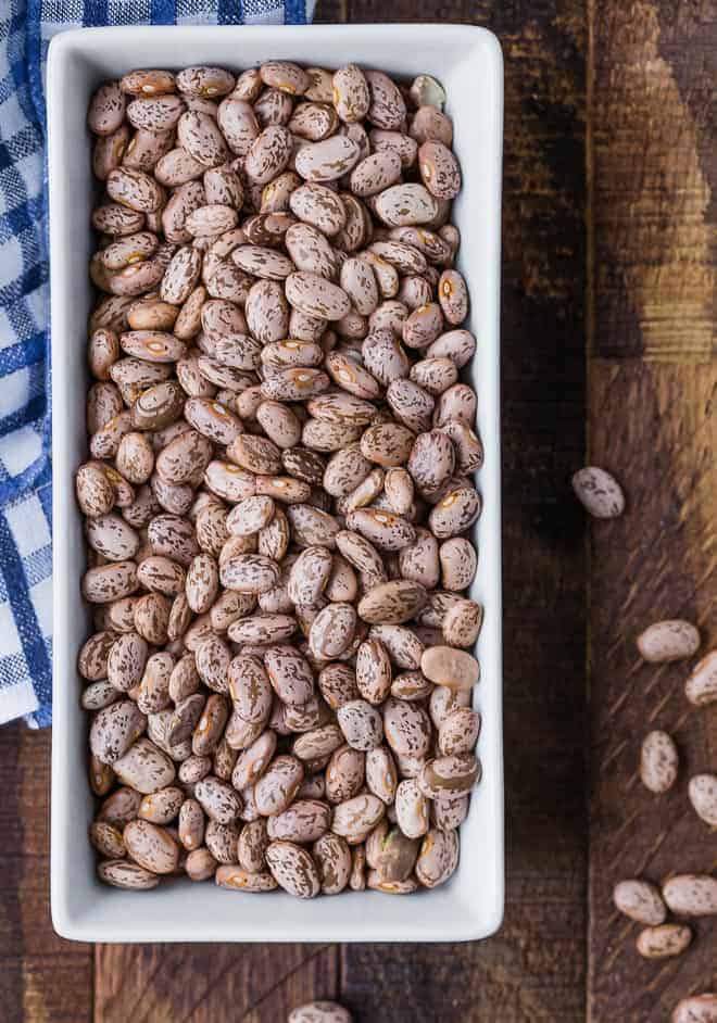 Image of dry pinto beans in a white rectangular dish.