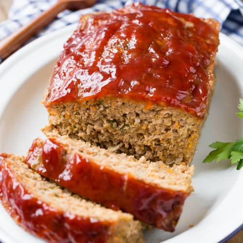 Image of moist meatloaf with a shiny tomato glaze, cut into slices.
