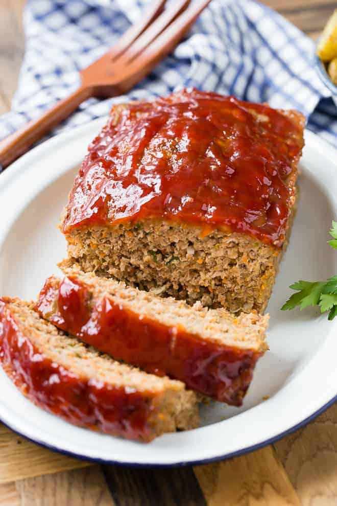 Image of moist meatloaf with a shiny tomato glaze, cut into slices. 