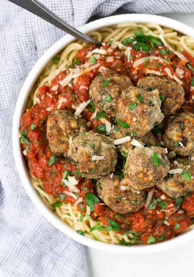 Image of a bowl of turkey meatballs on top of spaghetti and spaghetti sauce. 