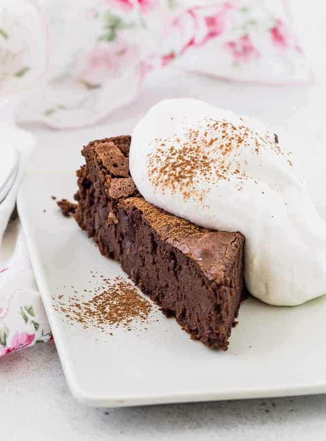 Image of chocolate chile cake sliced on a plate with whipped cream.