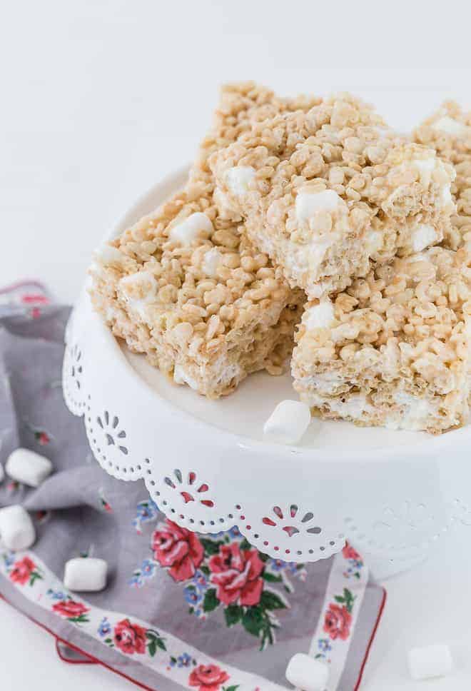 Image of rice krispies marshmallow bars on a white cake stand. 