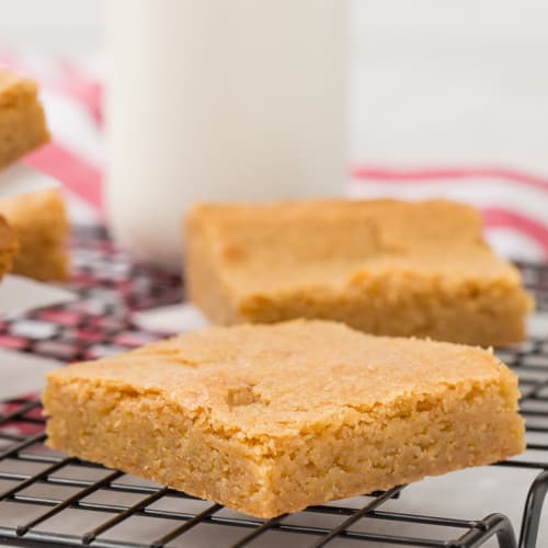 Image of easy, rich blondies on a cooling rack with milk in the background.