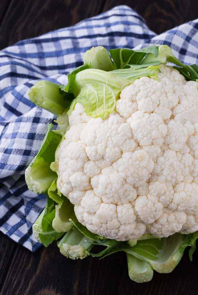 Head of cauliflower on a dark surface with a blue and white linen.