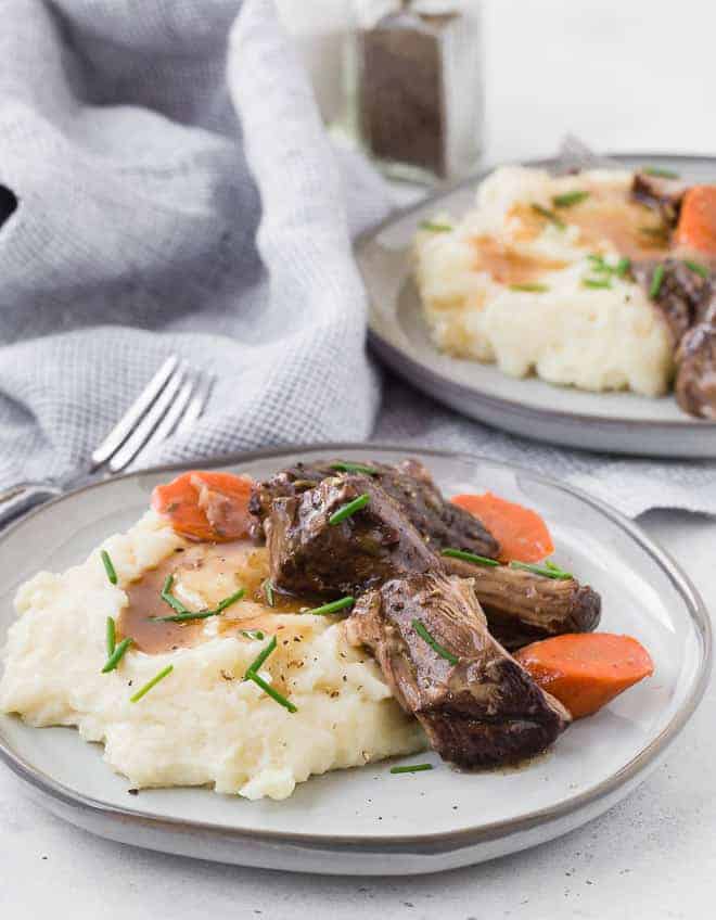 Image of two plates of melt in your mouth, tender beef roast with mashed potatoes, gravy, and carrots. 