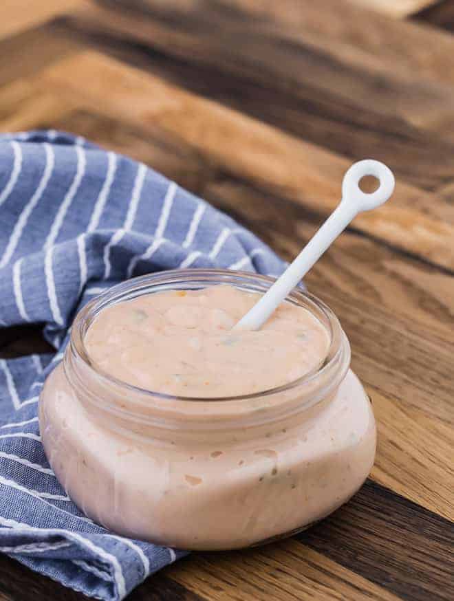 Image of homemade thousand island dressing in a jar with a small white spoon.