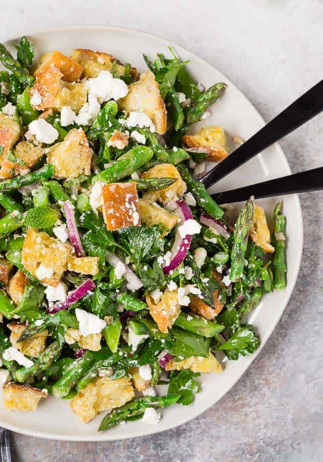 Image of a fresh green spring salad made with asparagus, croutons, red onions, mint, and parsley.