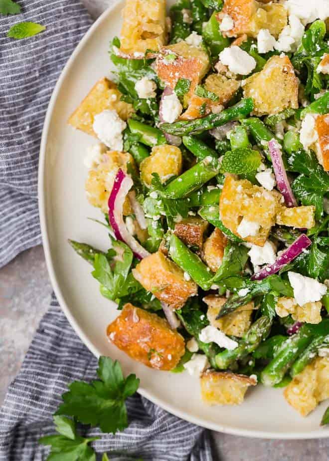 Image of asparagus panzanella salad, croutons, red onions, feta, asparagus, and fresh mint, finished with a homemade red wine vinaigrette.