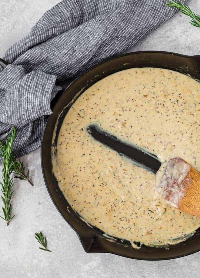 Image of creamy dijon sauce in a frying pan with a wooden spoon being pulled through it.
