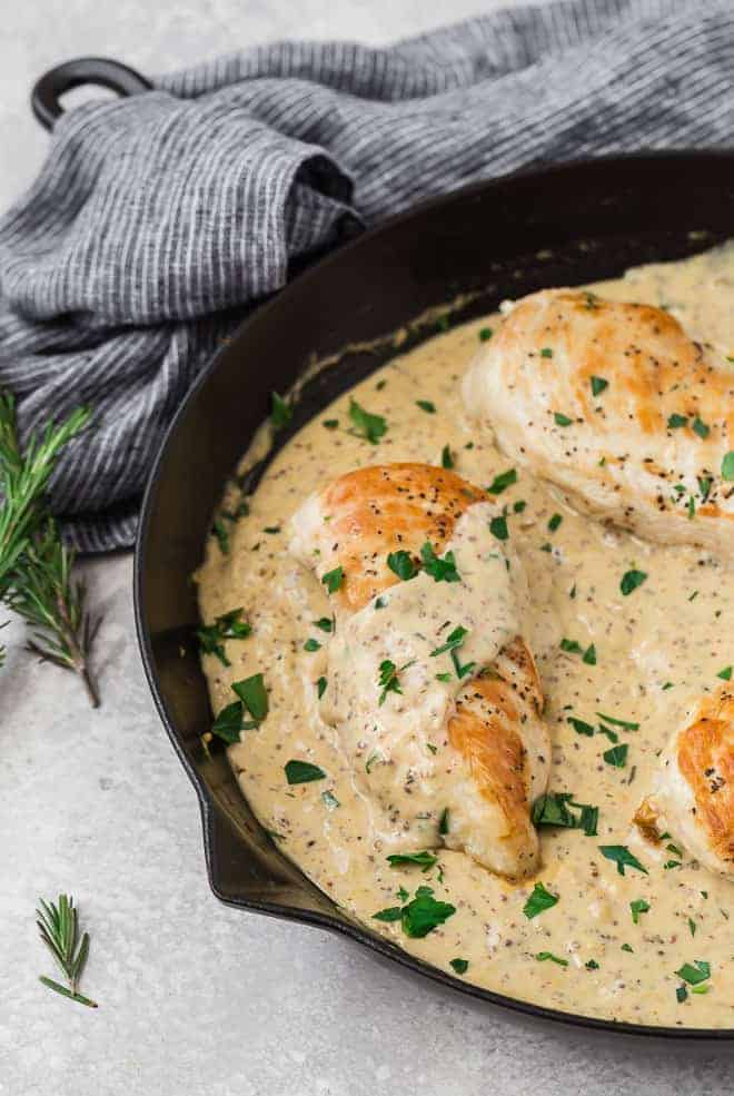 Image of chicken breasts in a creamy light yellow mustard sauce, flecked with fresh parsley.