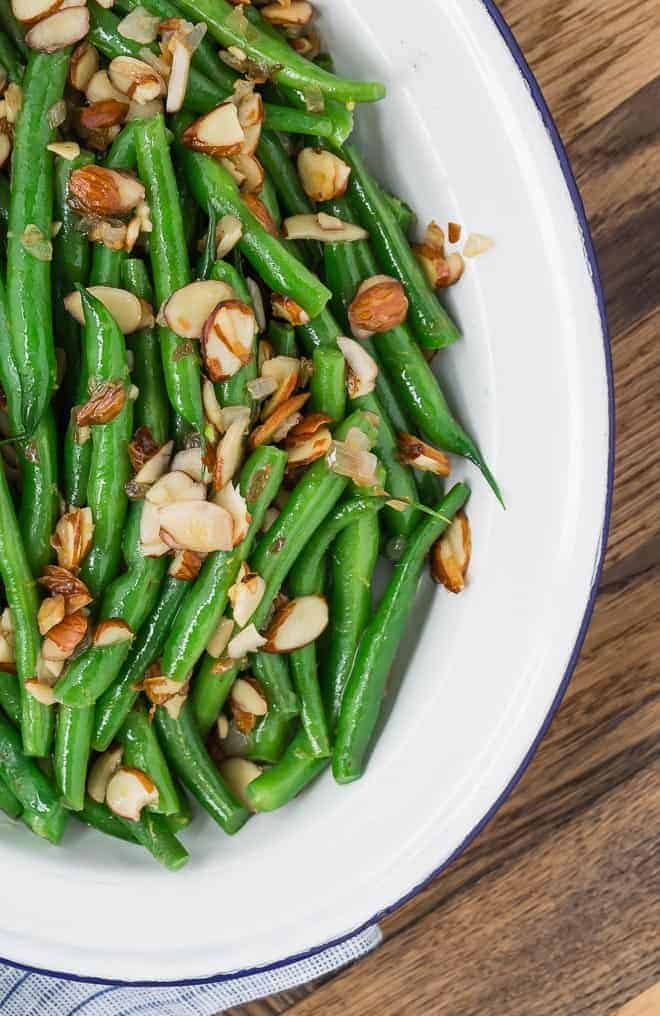 Image of green beans almondine, bright green and garnished with almonds and lemon zest.