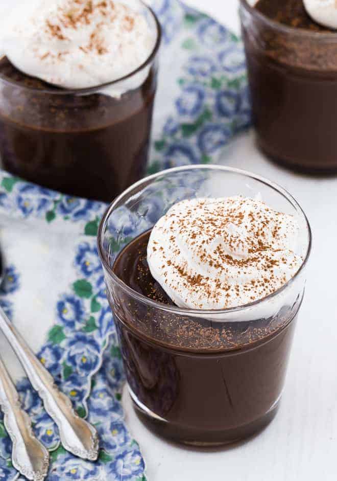 Image of chocolate pudding in a small glass, topped with fluffy homemade whipped cream.