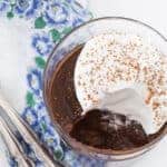Image of chocolate pudding that has been made from scratch, topped with whipped cream, with a spoonful removed from the bowl.