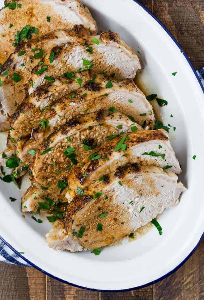 Image of an instant pot pork loin roast, drizzled in balsamic sauce, sliced and placed on a serving plate.