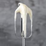 Image of an electric mixer beater with lemon cream cheese frosting on it.