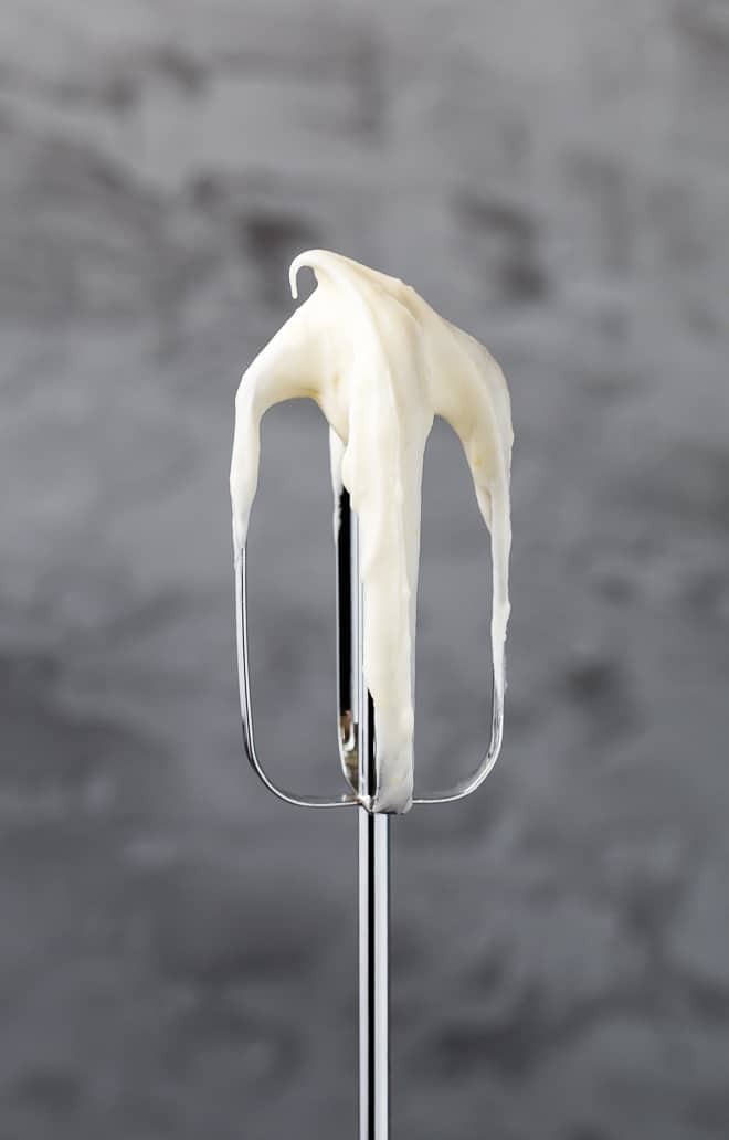 Image of an electric mixer beater with lemon cream cheese frosting on it.