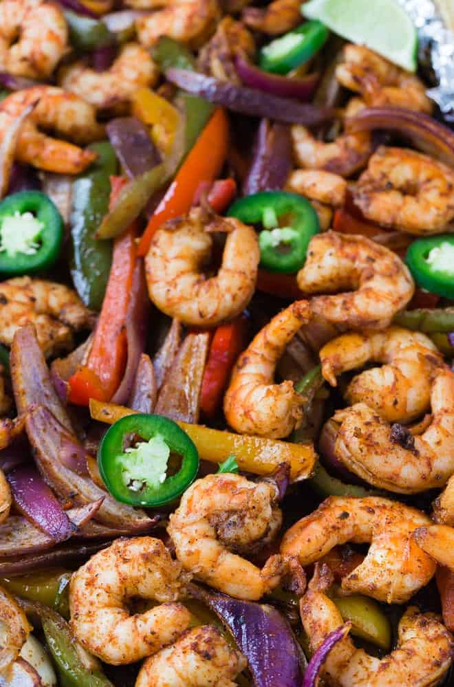 Close up view of sheet pan shrimp fajitas topped with fresh jalapeno peppers.