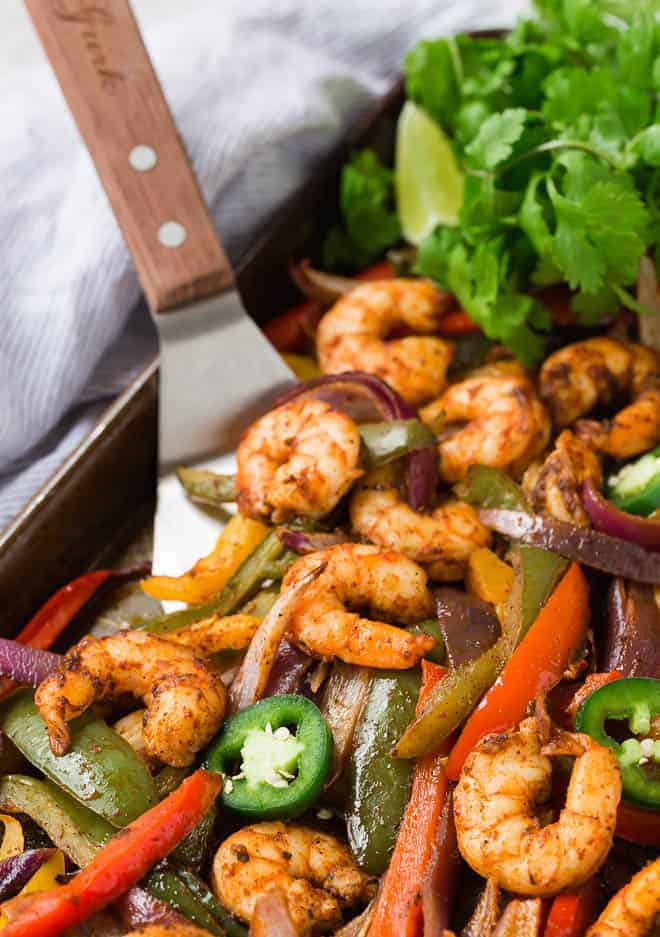 Sheet pan shrimp fajitas on a spatula.