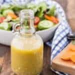 White wine vinegar salad dressing with a tossed salad pictured in the background of the photo.