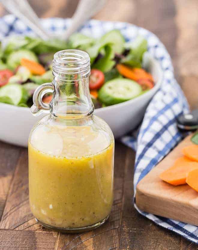 White wine vinegar salad dressing with a tossed salad pictured in the background of the photo.