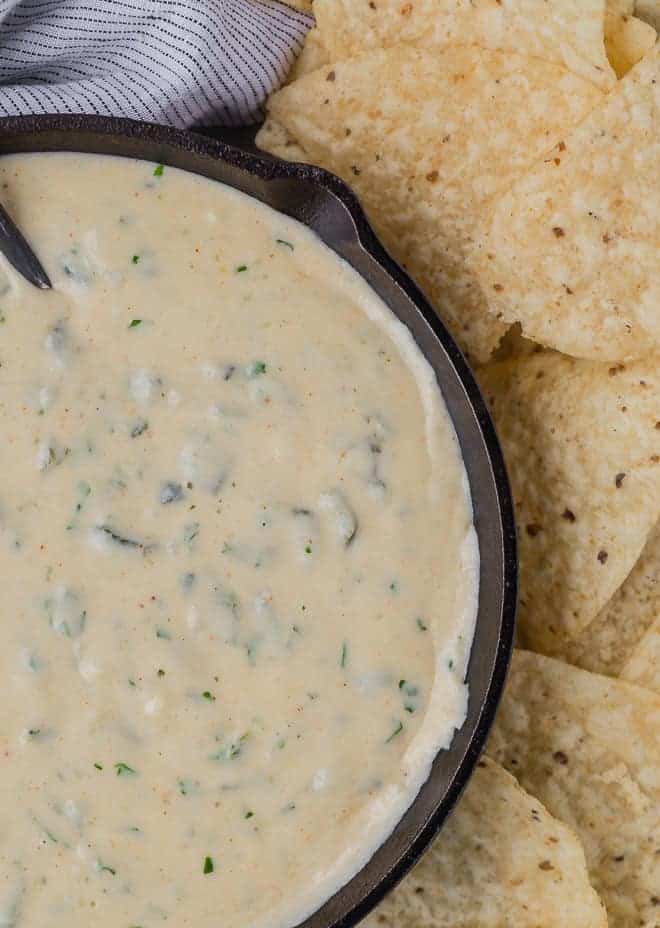 Close up overhead view of queso in a black skillet, next to a pile of chips. 