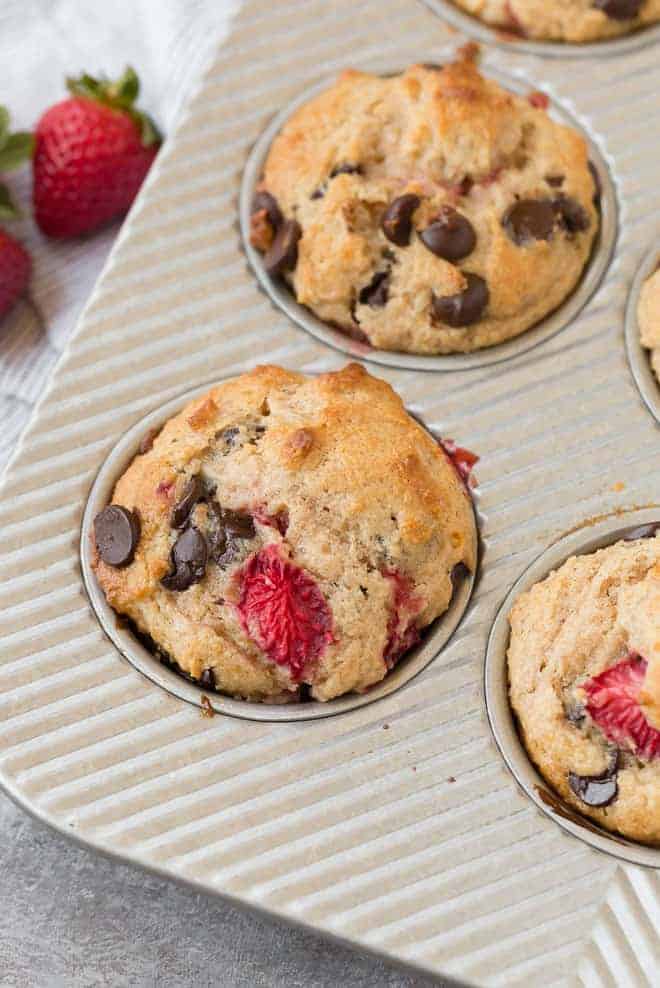 Image of fluffy whole wheat muffins with strawberries and chocolate chips in a muffin tin.