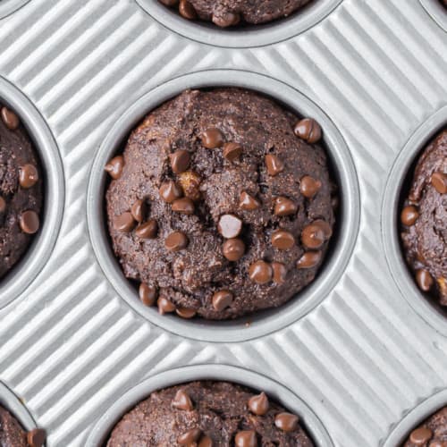 Overhead view of a close up of a chocolate muffins with chocolate chips.