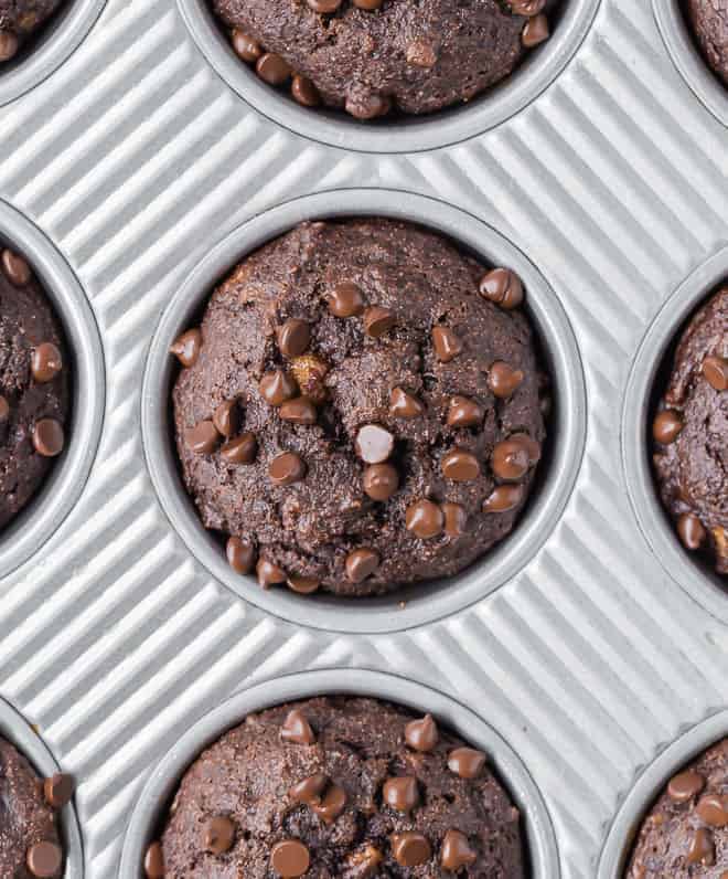 Overhead view of a close up of a chocolate muffins with chocolate chips.