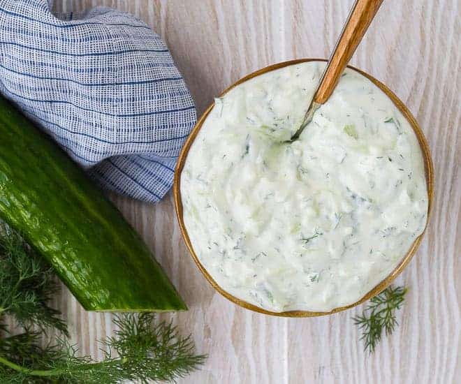 Overhead view of a bowl of creamy yogurt sauce made with tomatoes, dill, and lemon. 