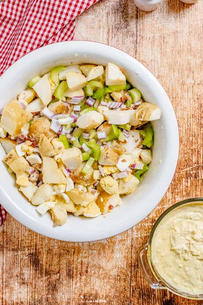 A bowl of potato salad ingredients being mixed together.