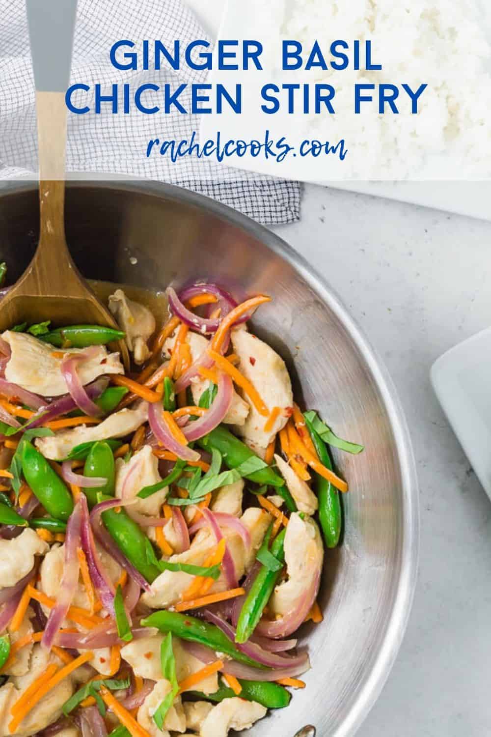 Overhead view of a wok filled with white rice, chicken, sugar snap peas, carrots, and red onions in stir fry form. It is garnished with fresh basil ribbons.