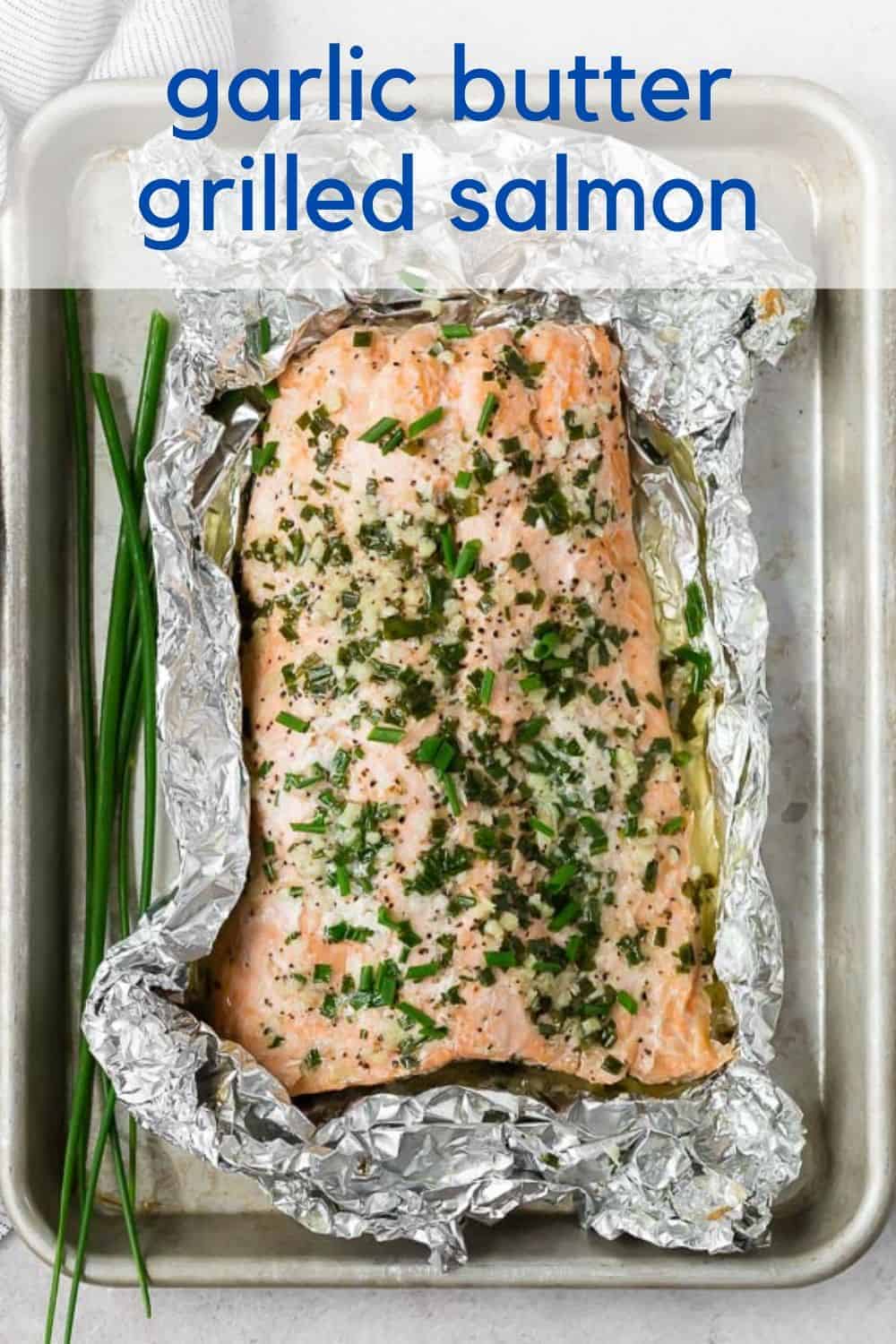 Overhead view of grilled salmon in a foil pack. Text overlay reads "garlic butter grilled salmon."