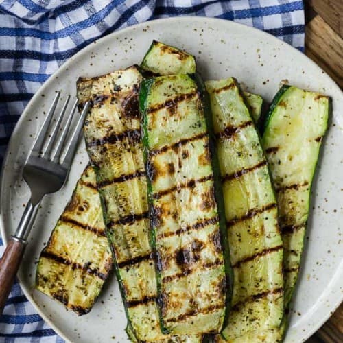 Overhead view of a plate of zucchini slices that have been grilled.